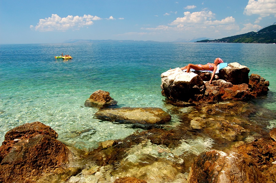 Young girl is sunbathing on a rocky beach in Croatia